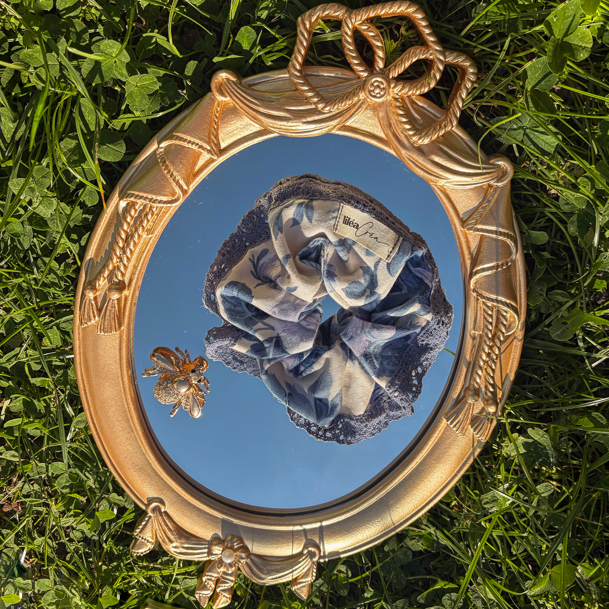 chouchou isaline modele fleurs bleues dentelle 5 chouchou isaline modèle fleurs bleues dentelle posé sur un miroir vintage dans l'herbe