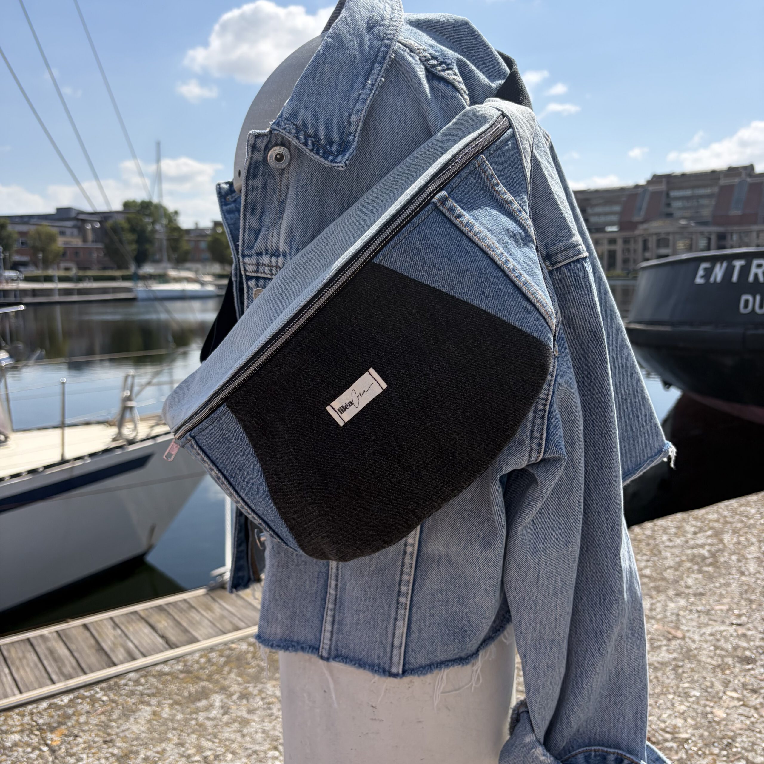 sac banane isabelle modele jean 1 sac demi lune marcelle modèle marin accroché sur une borne avec une veste en jean en bord de mer